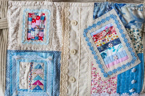 fashion, handcraft, patchwork, sewing concept - colorful textile fragment made of bright snippets with various prints, buttons, lace and embroidery for decorating