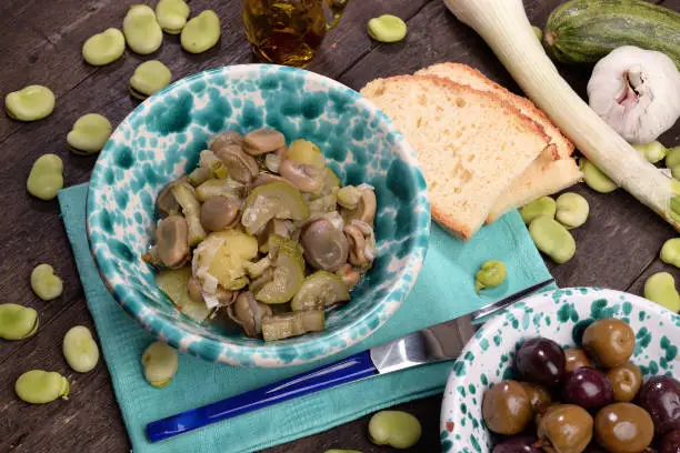 Bowl of wet beans with onion and oregano and olives on marble table