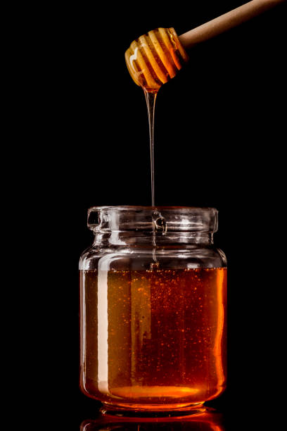 istock Honey dipper dripping honey into glass jar 681419766