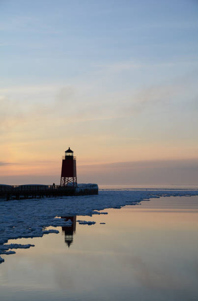 istock A red lighthouse reflects in water with snow and ice at sunset 681457740