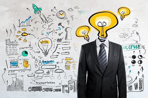 Light bulb headed businessman on concrete background with business sketch. Successful idea concept