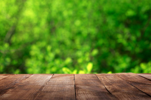 Empty wooden table with blur green leaves bokeh background