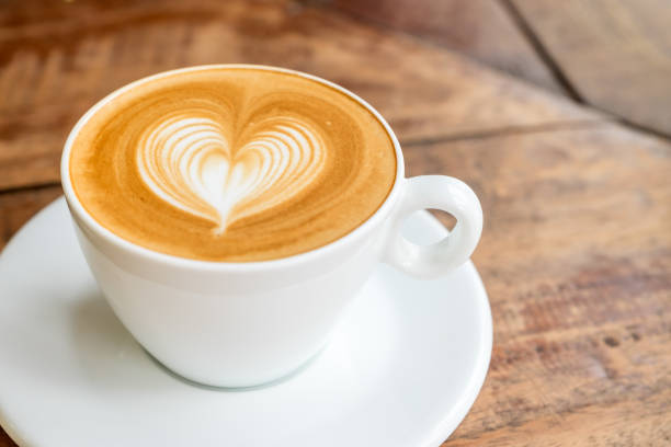 istock Close up white coffee cup with heart shape latte art on wood table at cafe 681614794