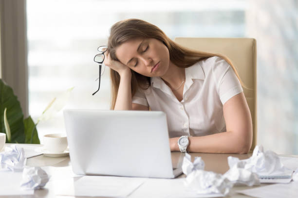 Businesswoman sleeping with head on hand at work Businesswoman sleeping with head on hand at the desk. Sleepy girl dozing at workplace. Tired female office worker suffering from lack of sleep. Lazy girl bored routine. After-hours work in office narcolepsy stock pictures, royalty-free photos & images