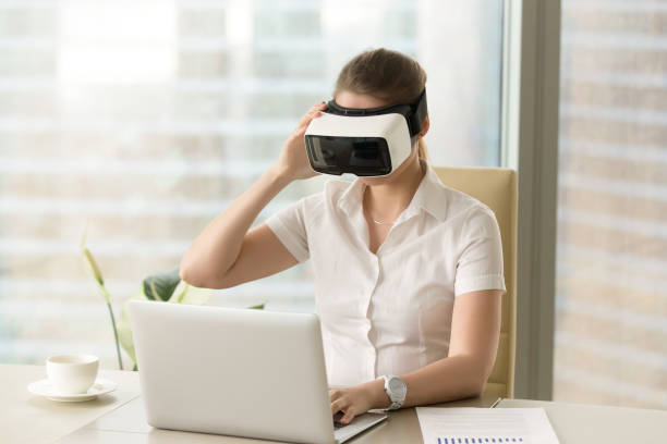 istock Businesswoman synchronizes VR headset with laptop 681625492