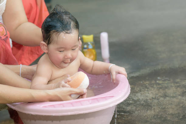 Asian baby girl playing sponge during bathing. stock photo