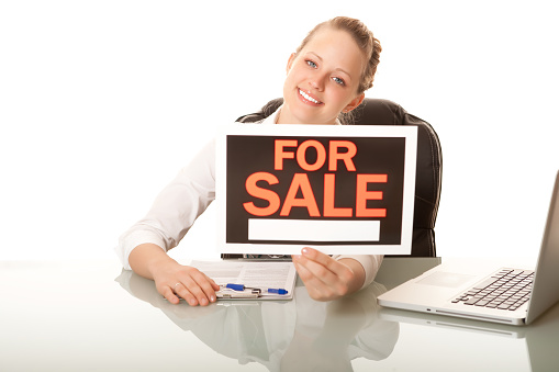 Real estate agent holding sale sign
