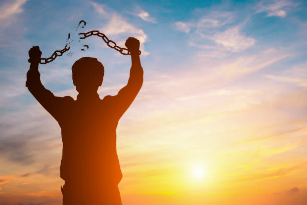 silhouette image of a businessman with broken chains in sunset - business slave imagens e fotografias de stock