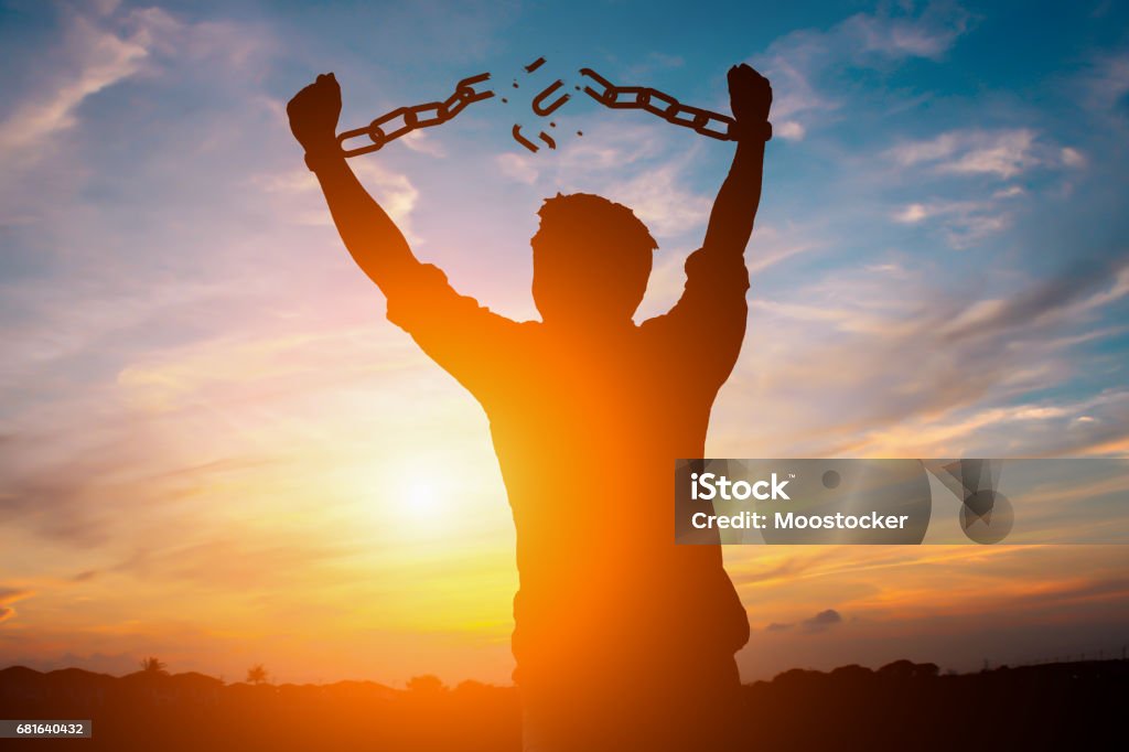 Silhouette image of a businessman with broken chains in sunset Freedom Stock Photo