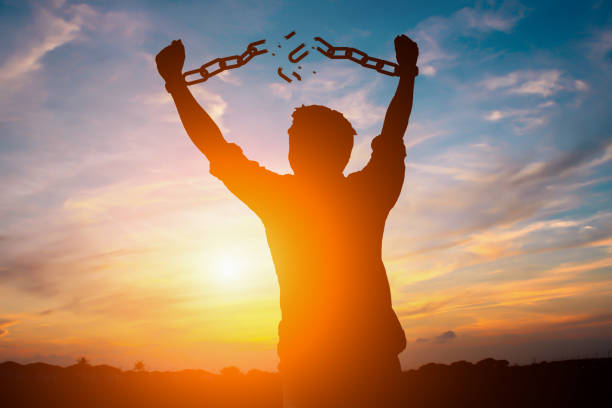 Silhouette image of a businessman with broken chains in sunset Silhouette image of a businessman with broken chains in sunset freedom stock pictures, royalty-free photos & images