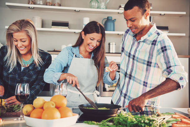 istock Three friends frying food in pan together 681656340