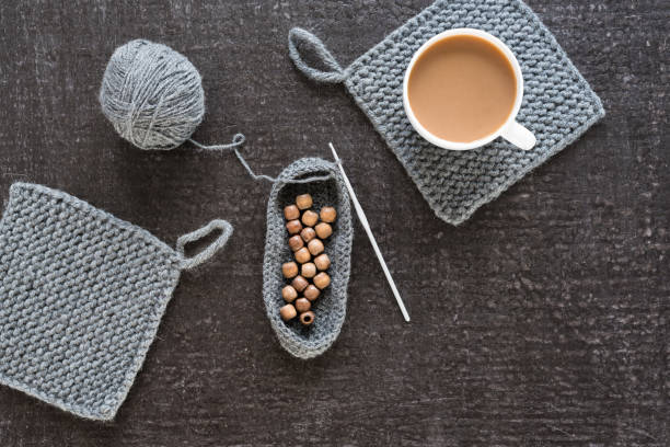 Cup of coffee, wooden beads and grey crocheting on a black background.