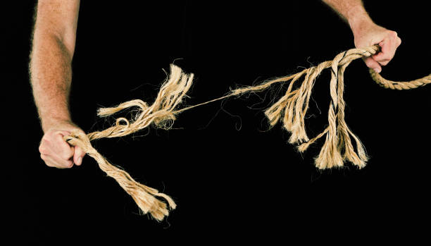 istock Masculine hands grip rope, pulling apart. Strength or stress metaphor. 681727286