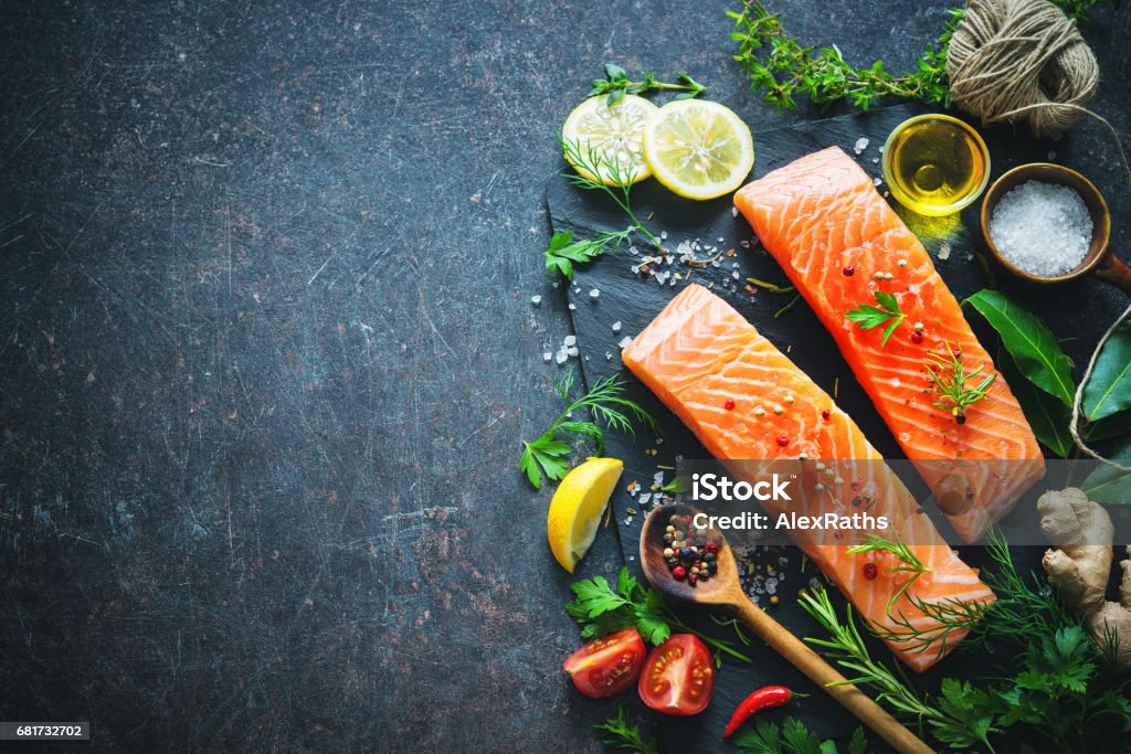 Fresh salmon fillet with aromatic herbs, spices and vegetables Fresh salmon fillet with aromatic herbs, spices and vegetables. Balanced diet or cooking concept Salmon - Seafood Stock Photo