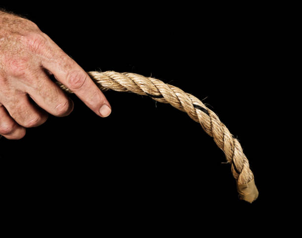 istock Masculine hand grips drooping rope: implications of impotence. Black background. 681732728
