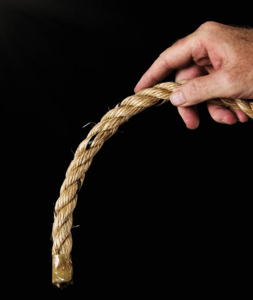 istock Masculine hand grips drooping rope: implying erectile dysfunction. Black background. 681733274