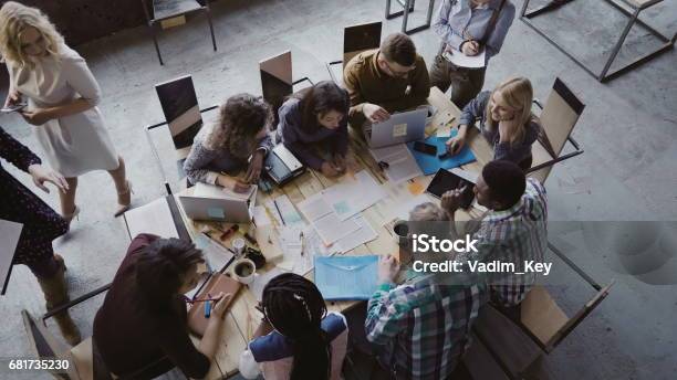 Top View Of Mixed Race Business Team Sitting At The Table At Loft Office And Working Woman Manager Brings The Document Stock Photo - Download Image Now