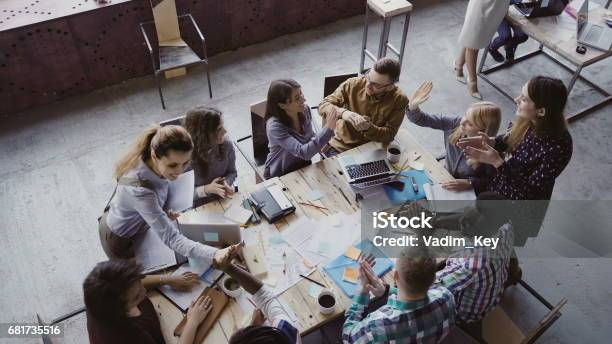 Top View Of Creative Business Team Working At Modern Office Colleagues Talking Smiling High Five With Each Other Stock Photo - Download Image Now