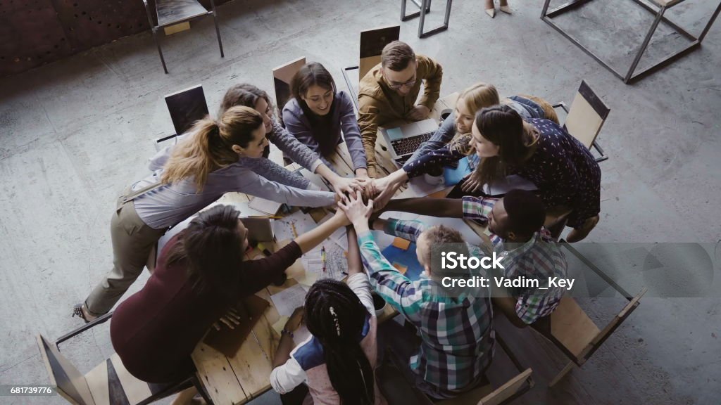 Vista superior del equipo de negocio trabajando en oficina de loft moderno. Grupo de jóvenes mestizos de personas reúne palm centro - Foto de stock de Micromecenazgo libre de derechos