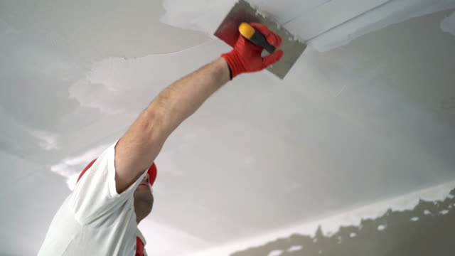 Construction worker sanding a drywall.