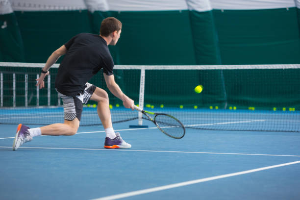 le jeune homme dans un court de tennis fermé avec ballon - indoor tennis photos et images de collection