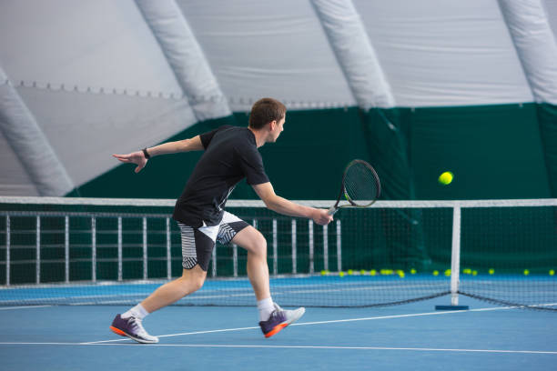 o jovem em uma quadra de tênis fechada com bola - tennis court indoors net - fotografias e filmes do acervo