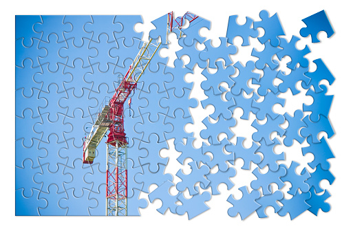 Tower crane against a blue background in puzzle shape - concept image