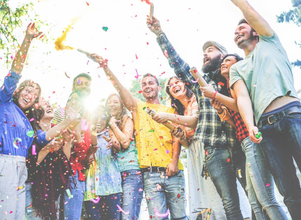 szczęśliwi przyjaciele cieszący się imprezą, rzucanie konfetti i używanie kolorów bomb dymowych na imprezie na świeżym powietrzu - celebration confetti party summer zdjęcia i obrazy z banku zdjęć