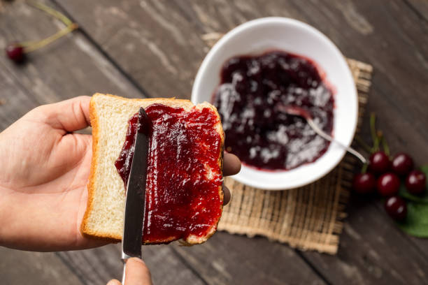 istock Man is preparing breakfast and spreading marmalade on toast 681773776