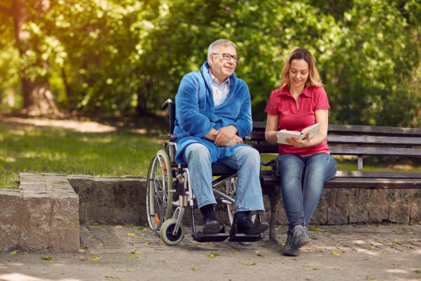 istock Disabled man in park spending time together with his daughter reading book 681784940