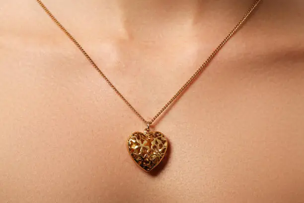 Golden heart pendant. Beauty and jewelry concept. Woman wearing shiny gold pendant. Fashion portrait of beautiful luxury woman with jewelry. Gift for Valentines day"r"n"r"n
