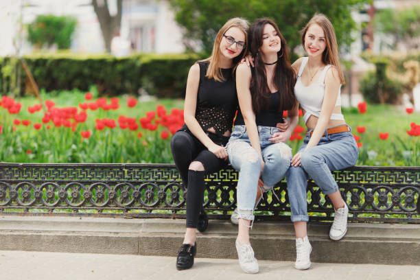 istock Three girls sit on the park background 681803324