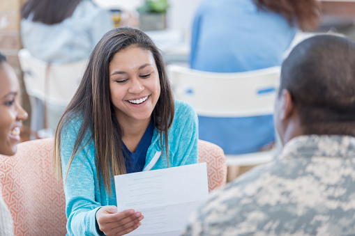 Cheerful female high school or college students talk with military recruiter at recruitment event.