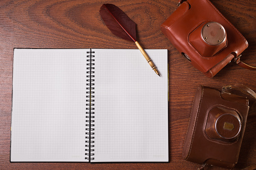 a sheet of paper from a notebook, fountain pen and case for the camera on wooden background, copyspace
