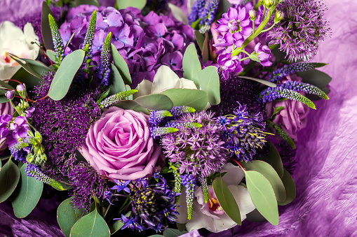 Purple bouquet with a variety of colors. Roses, hydrangeas, lilacs, greens, leaves, orchids. Background of flowers