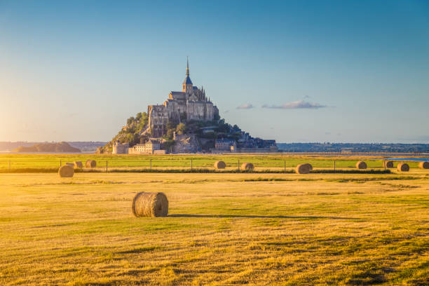 Le Mont Saint-Michel at sunset, Normandy, France Beautiful view of famous historic Le Mont Saint-Michel in golden evening light at sunset in summer with hay bales on fields with retro vintage Instagram style pastel filter effect, Normandy, France marazion photos stock pictures, royalty-free photos & images
