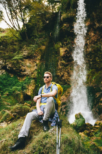 istock Young hiker stopped beside a mountain waterfall to rest 681829522