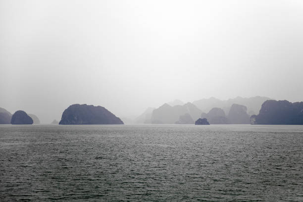 Boats floating on Ha Long Bay in Vietnam with dramatic limestone cliffs and overcast skies. High quality photo