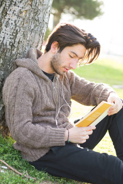 istock Young man reading book in the park 681848692