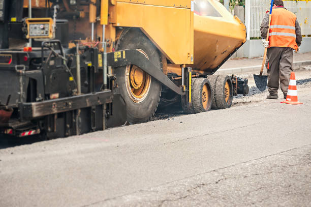 istock Worker with shovel checks the work of  asphalt pavement machine. 681848712