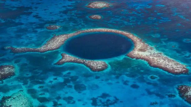 Aerial view down to the famous diving site and natural phenomenon - the Blue Hole in the Lighthouse Reef, East of the Turneffe Atoll in Caribbean Sea, Belize, Central America.
