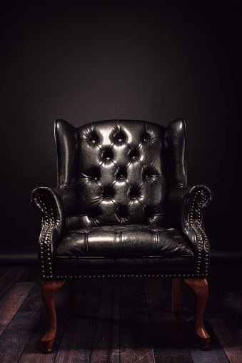 Black vintage leather armchair boss on a black background