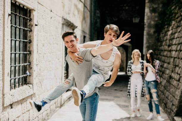 istock Handsome boy carrying a friend on his back is waving to camera 681868002