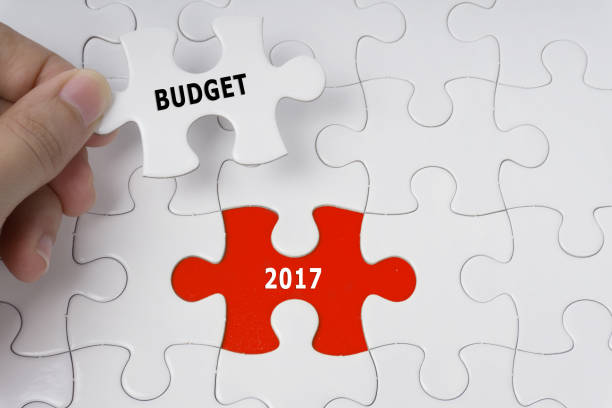 istock Hand holding piece of jigsaw puzzle with words Budget 2017. 681868870