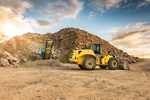 Outdoor quarry with heavy machinery, silos and mechanical tape for stone transport