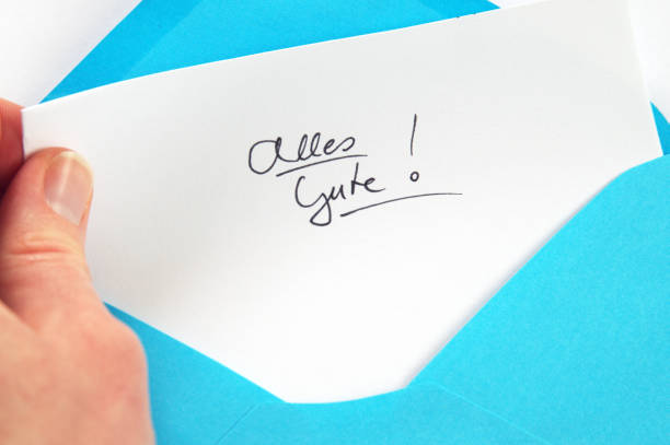 istock Alles Gute (All the best), hand holding handwritten letter in blue envelope 681875602