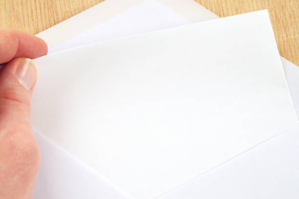 istock hand pulling blank sheet of paper from white envelope, wooden background 681877438