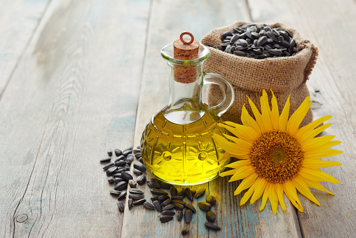 Sunflower oil in bottles with  seeds and flower on wooden background