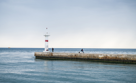 Manavgat harbour entrance and lighthouse with man fishing, bad weather