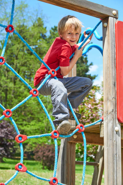 istock Child boy climbing rope web on the children playground outdoors at summer 681890964